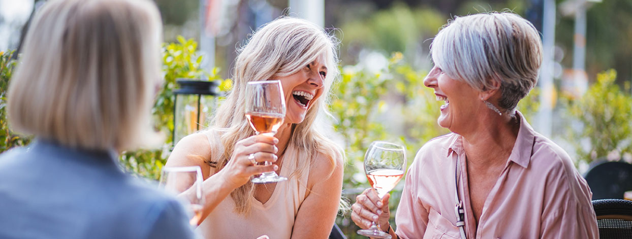 senior women drinking wine together outside