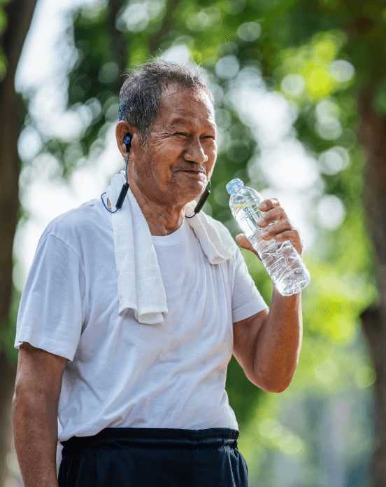 Senior man drinks water during workout outdoors