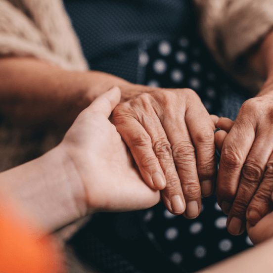 Senior and caregiver holding hands