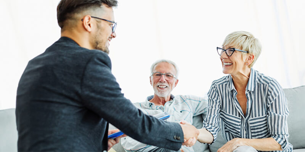 Senior woman and man shaking hands with professional man in home